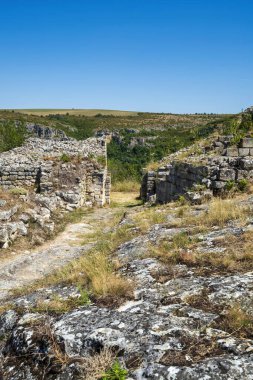 Bulgaristan 'daki ortaçağ Cherven Kalesi' nin antik taş kalıntıları ve savunma duvarları derin bir nehir geçidine tünemiş ve engebeli uçurumlar ve yaz bitkileriyle çevrili..