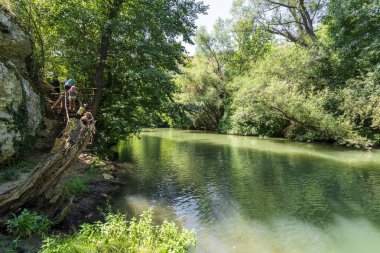 Bulgaristan 'ın Rusenski Lom Nehri - 10 Ağustos 2025: Ziyaretçiler, Bulgaristan' da kayalık kayalıklar ve yoğun yeşilliklerle çevrili Rusenski Lom nehri kıyısında kırsal bir patikada yürüyor.