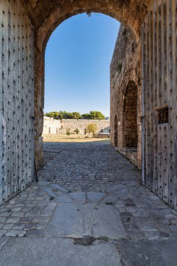 Yunanistan 'daki Pylos Kalesi' nin içindeki kemerli kapı, ahşap kapılar, taş duvarlar ve parlak avluya çıkan kaldırım taşı zemin..