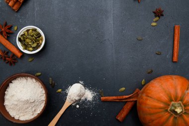 Baharatlar, portakal kabağı, tohumlar, siyah masada un. Sonbahar menüsü ya da sonbahar ev yapımı yemek konsepti. Ev mutfağı, Şükran Günü, üst manzara.