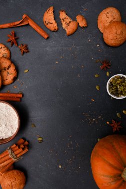 Baharatlar, portakal kabağı, tohumlar, mekik ve un dolu kırık kurabiyeler siyah masada. Sonbahar menüsü ya da fırın konsepti. Sonbahar, ev yapımı hamur işi, şükran günü, üst manzara.
