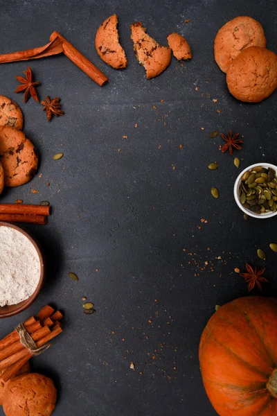 Baharatlar, portakal kabağı, tohumlar, mekik ve un dolu kırık kurabiyeler siyah masada. Sonbahar menüsü ya da fırın konsepti. Sonbahar, ev yapımı hamur işi, şükran günü, üst manzara.