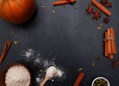 Baharatlar, portakal kabağı, tohumlar, siyah masada un. Sonbahar menüsü ya da sonbahar ev yapımı yemek konsepti. Ev mutfağı, Şükran Günü, üst manzara.