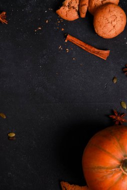 Baharatlar, portakallı balkabağı, siyah masadaki kırık kurabiyeler. Sonbahar menüsü ya da fırın konsepti. Sonbahar, ev yapımı hamur işi, şükran günü, üst manzara.