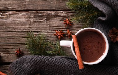 Bir kupa çikolata, baharat, gri örgü eşarp, köknar ağacı dalları, ahşap masa zemininde koniler. Kış içkisi ve Noel konsepti. Baharatlı kakao, yeni yıl, üst görünüm, kopyalama alanı, yakın plan