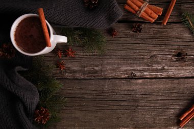 Bir fincan çikolata, baharat, gri örgü eşarp, köknar ağacı dalları, ahşap masa zemininde koniler. Kış içkisi ve Noel konsepti. Baharatlı kakao, yeni yıl, üst görünüm, kopyalama alanı