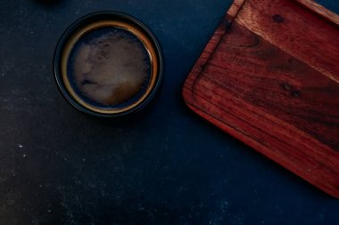 Espresso bardağı ve boş tahta altlık. Sade kahve fincanı, çimento masa arkasında Americano. Kafe şablonları, kafe, kahvaltı konsepti için. Üst görünüm