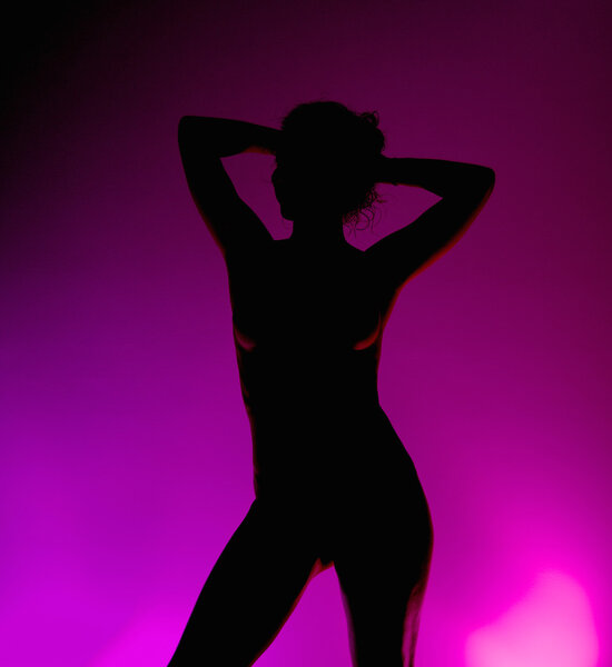 The silhouette of a naked beautiful girl with purple light in the background