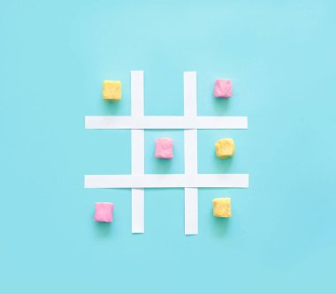 Mavi arka planda pembe ve sarı şekerlemelerden yapılmış tik tak parmak.