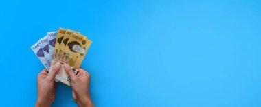 Mavi arka planda Kore 'yi tutan iki el para kazandı. Finans sektörü ve bankacılık kavramı.