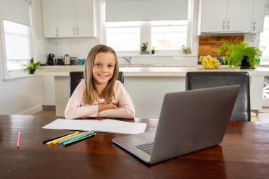 Bilgisayarda online ders izleyen mutlu liseli kız kendini izole bir şekilde evde öğreniyor. Eğitim, Karantina ve Okullar COVID-19 nedeniyle kişisel öğrenimin yeniden başlatılması veya durdurulması.