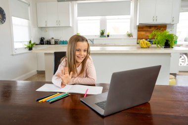 Bilgisayarda online ders izleyen mutlu liseli kız kendini izole bir şekilde evde öğreniyor. Eğitim, Karantina ve Okullar COVID-19 nedeniyle kişisel öğrenimin yeniden başlatılması veya durdurulması.