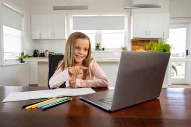 Bilgisayarda online ders izleyen mutlu liseli kız kendini izole bir şekilde evde öğreniyor. Eğitim, Karantina ve Okullar COVID-19 nedeniyle kişisel öğrenimin yeniden başlatılması veya durdurulması.