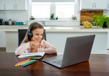 Bilgisayarda online ders izleyen mutlu liseli kız kendini izole bir şekilde evde öğreniyor. Eğitim, Karantina ve Okullar COVID-19 nedeniyle kişisel öğrenimin yeniden başlatılması veya durdurulması.