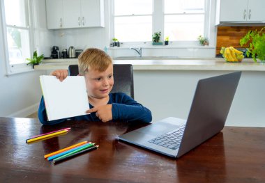 Happy Schoolboy on laptop watching online lesson learning remotely at home in self-isolation. Education, Quarantines and Schools reopening or shutting down in-person learning due to COVID-19 Pandemic. clipart