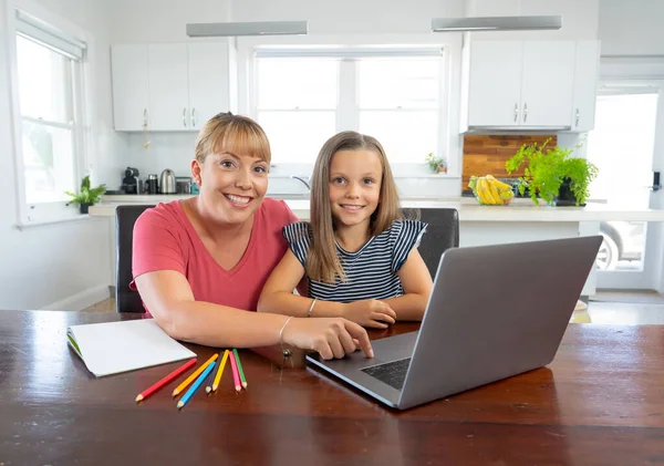 Mother helping child daughter studying at home in self-isolation or quarantine. Education, Home schooling, Remote learning and School closures due to Coronavirus second wave concept.