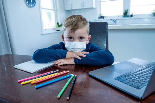 Yüz maskesi takmış okul çocuğu online eğitim hakkında sanal ders izliyor. Evde kendini soyutlanmış ve sıkılmış hissediyor. COVID-19 salgını nedeniyle uzak öğrenim ve kapalı okullar ikinci dalga.