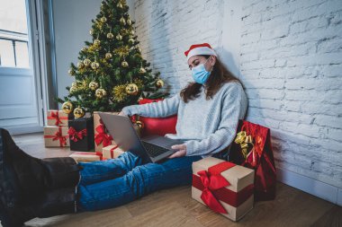 Yüz maskesi videosu olan üzgün kadın Noel 'de ailesini ve arkadaşlarını arıyor ve kendini evde yalnız hissediyor. COVID-19 sanal tatil kutlamaları, sosyal uzaklık, tecrit ve akıl sağlığı.