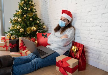 Yüz maskesi videosu olan üzgün kadın Noel 'de ailesini ve arkadaşlarını arıyor ve kendini evde yalnız hissediyor. COVID-19 sanal tatil kutlamaları, sosyal uzaklık, tecrit ve akıl sağlığı.
