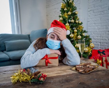 Maskeli üzgün kadın Noel 'de yalnız başına evde yalnız başına yas tutuyor ve ailesini ve arkadaşlarını özlüyor. COVID-19 Kış tatili ve akıl sağlığı süresince karantina ve tecrit.