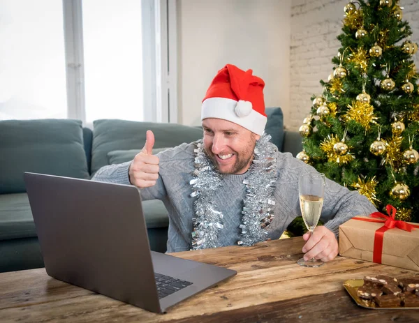 Happy man home alone in lockdown celebrating virtual christmas using laptop video calling family and friends. Virtual holiday gathering online due to coronavirus quarantines and social distancing.