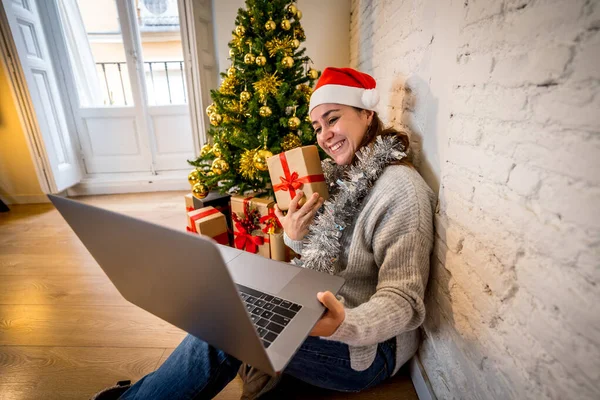 Happy woman alone in lockdown celebrating virtual christmas video calling family and friend. Virtual holiday gathering online due to coronavirus quarantine, social distancing and new restrictions.