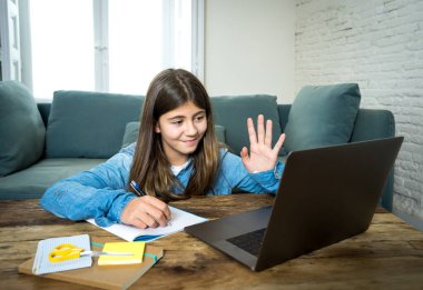 Bilgisayardaki mutlu genç kız evde internetteki sanal uzak sınıflarda ders çalışıyor çünkü lise son koronavirüs kilitlenmesi nedeniyle kapalı kalıyor. COVID-19, eğitim, çocuklar, E-öğrenme.