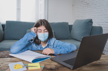 Sıkıcı ve depresif yüzlü genç kız evde online eğitim sınıfında ders çalışıyor çünkü lise yeni COVID-19 hava durumu ya da hava durumu nedeniyle kapalı..