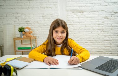 Bilgisayardaki Happy Liseli Kız son koronavirüs kilitlenmesi nedeniyle okullar kapalı kaldığı için evdeki internetteki sanal uzak bir sınıfta ders çalışıyor. COVID-19, eğitim, çocuklar ve E-öğrenim.
