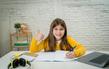 Bilgisayardaki Happy Liseli Kız son koronavirüs kilitlenmesi nedeniyle okullar kapalı kaldığı için evdeki internetteki sanal uzak bir sınıfta ders çalışıyor. COVID-19, eğitim, çocuklar ve E-öğrenim.