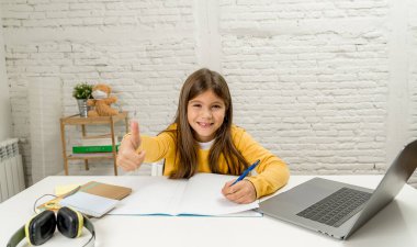 Bilgisayardaki Happy Liseli Kız son koronavirüs kilitlenmesi nedeniyle okullar kapalı kaldığı için evdeki internetteki sanal uzak bir sınıfta ders çalışıyor. COVID-19, eğitim, çocuklar ve E-öğrenim.