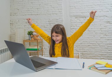 Bilgisayardaki Happy Liseli Kız son koronavirüs kilitlenmesi nedeniyle okullar kapalı kaldığı için evdeki internetteki sanal uzak bir sınıfta ders çalışıyor. COVID-19, eğitim, çocuklar ve E-öğrenim.