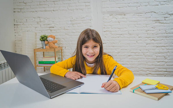 Happy Schoolgirl on laptop studying online in a virtual remote class on the internet at home as schools remain closed due to latest coronavirus lockdown. COVID-19, education, children and E- learning.