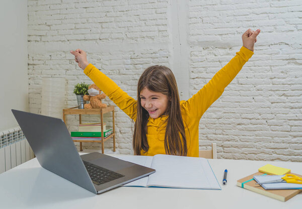 Happy Schoolgirl on laptop studying online in a virtual remote class on the internet at home as schools remain closed due to latest coronavirus lockdown. COVID-19, education, children and E- learning.