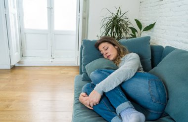 Üzgün, üzgün, çekici bir kadın evdeki kanepede ağlıyor. Yalnız hissediyor, yorgun ve endişeli. Akıl sağlığı, yalnızlık ve yalnızlık yüzünden depresyonda. Psikoloji, yalnızlık ve insanlar