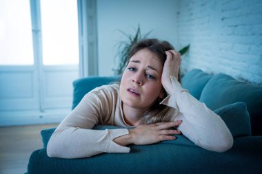 Üzgün, üzgün, çekici bir kadın evdeki kanepede ağlıyor. Yalnız hissediyor, yorgun ve endişeli. Akıl sağlığı, yalnızlık ve yalnızlık yüzünden depresyonda. Psikoloji, yalnızlık ve insanlar