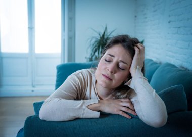 Üzgün, üzgün, çekici bir kadın evdeki kanepede ağlıyor. Yalnız hissediyor, yorgun ve endişeli. Akıl sağlığı, yalnızlık ve yalnızlık yüzünden depresyonda. Psikoloji, yalnızlık ve insanlar