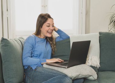Zoom videosundaki mutlu genç kadın laptopunu kullanarak arkadaşlarını arıyor. Coronavirus tecridi ve sosyal uzaklık sırasında aileyle çevrimiçi sohbet. Bağlı kal, evde kal konsepti.