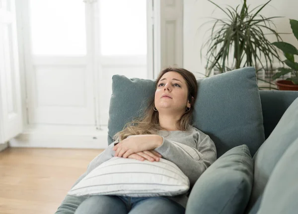 Depressed sad attractive woman crying on sofa couch at home feeling lonely tired and worried suffering depression in mental health, loneliness and isolation concept. Psychology, solitude and people