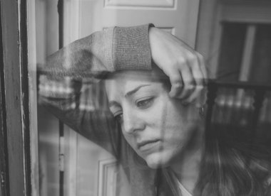 Genç, depresif, mutsuz, beyaz bir kadın. Evinin penceresinden endişeli ve üzgün görünüyor. Değersiz ve acı içinde hissediyorum. Yakın plan. Depresyon ve Akıl Sağlığı Konsepti