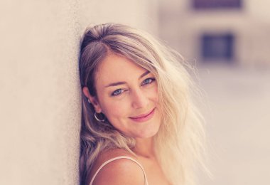 Açık havada, güzel sarı saçları ve şehvetli gülüşü olan çekici genç bir kadının portresi var. Doğal güzellik ve ışıkla poz veren kadın model. Gerçek insanlar, güzellik, moda ve yaşam tarzı.