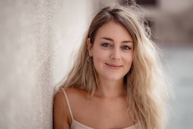 Açık havada, güzel sarı saçları ve şehvetli gülüşü olan çekici genç bir kadının portresi var. Doğal güzellik ve ışıkla poz veren kadın model. Gerçek insanlar, güzellik, moda ve yaşam tarzı.