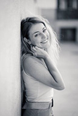 Açık havada, güzel sarı saçları ve şehvetli gülüşü olan çekici genç bir kadının portresi var. Doğal güzellik ve ışıkla poz veren kadın model. Gerçek insanlar, güzellik, moda ve yaşam tarzı.