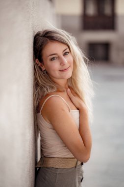 Açık havada, güzel sarı saçları ve şehvetli gülüşü olan çekici genç bir kadının portresi var. Doğal güzellik ve ışıkla poz veren kadın model. Gerçek insanlar, güzellik, moda ve yaşam tarzı.