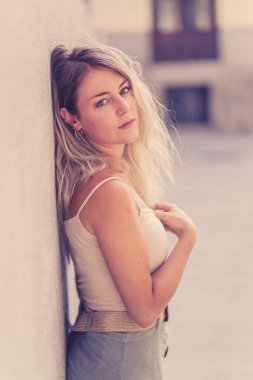 Açık havada, güzel sarı saçları ve şehvetli gülüşü olan çekici genç bir kadının portresi var. Doğal güzellik ve ışıkla poz veren kadın model. Gerçek insanlar, güzellik, moda ve yaşam tarzı.