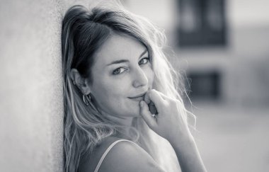 Açık havada, güzel sarı saçları ve şehvetli gülüşü olan çekici genç bir kadının portresi var. Doğal güzellik ve ışıkla poz veren kadın model. Gerçek insanlar, güzellik, moda ve yaşam tarzı.