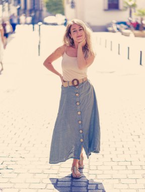 Açık havada, güzel sarı saçları ve şehvetli gülüşü olan çekici bir kadının uzun boylu portresi. Doğal güzellik ve ışıkla poz veren kadın model. Gerçek insanlar, güzellik, moda ve yaşam tarzı.