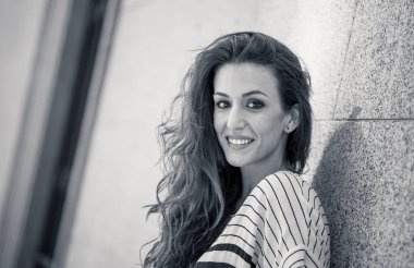 Açık havada, kıvırcık kızıl saçlı ve şehvetli gülüşlü çekici bir kadının portresi var. Doğal güzellikteki şehir geçmişine sahip bir kadın model. Gerçek insanlar, güzellik, moda ve yaşam tarzı.