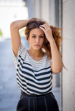 Açık havada, kıvırcık kızıl saçlı ve şehvetli gülüşlü çekici bir kadının portresi var. Doğal güzellikteki şehir geçmişine sahip bir kadın model. Gerçek insanlar, güzellik, moda ve yaşam tarzı.