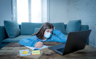 Sıkıcı ve depresif yüzlü genç kız evde online eğitim sınıfında ders çalışıyor çünkü lise yeni COVID-19 hava durumu ya da hava durumu nedeniyle kapalı..